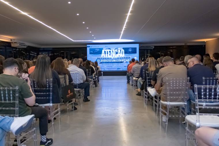 Congresso lotado em formato auditório, com palco e telão